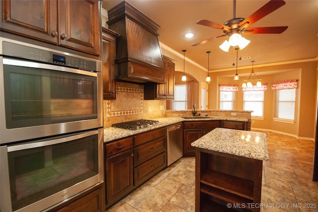 kitchen featuring sink, premium range hood, stainless steel appliances, decorative light fixtures, and kitchen peninsula