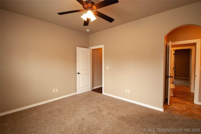 empty room featuring ceiling fan and dark carpet