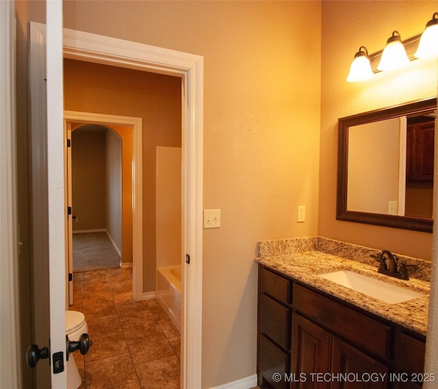 bathroom featuring tile patterned flooring, vanity, a washtub, and toilet