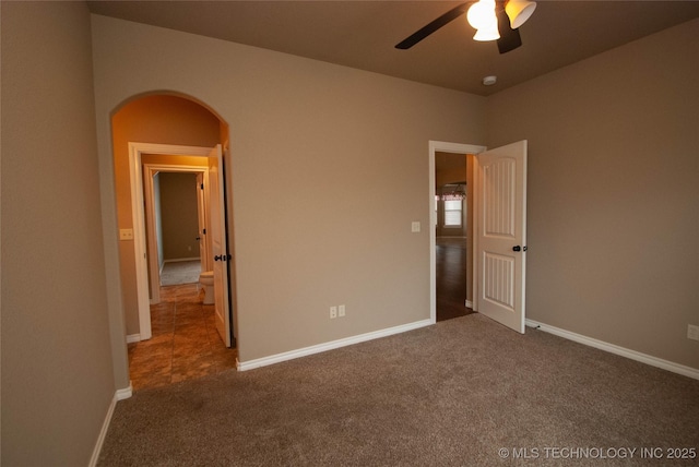 unfurnished bedroom with ceiling fan and dark carpet