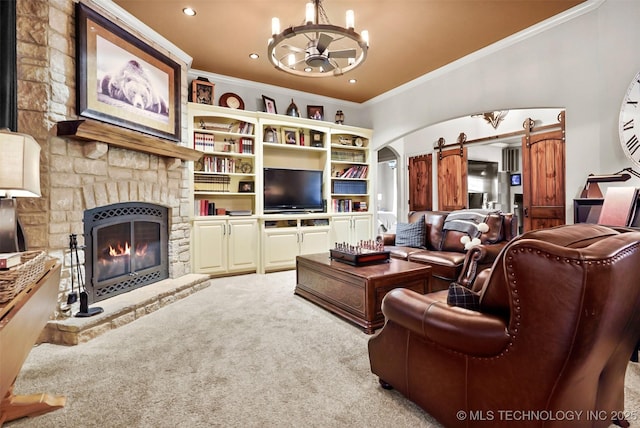 carpeted living room with a notable chandelier, a stone fireplace, ornamental molding, and a barn door