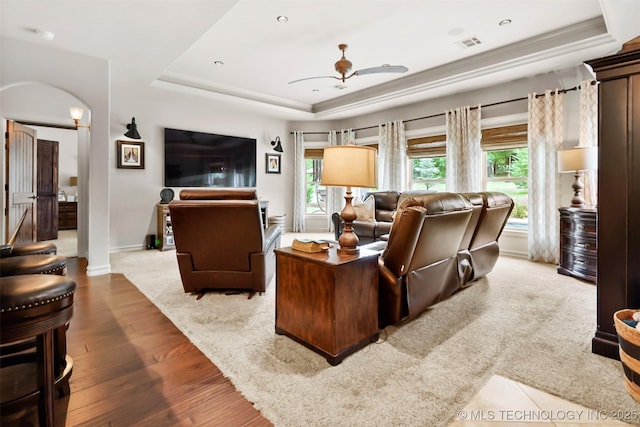 living room with a tray ceiling, light hardwood / wood-style flooring, and ceiling fan