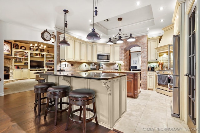 kitchen with a raised ceiling, a breakfast bar area, hanging light fixtures, kitchen peninsula, and stainless steel appliances