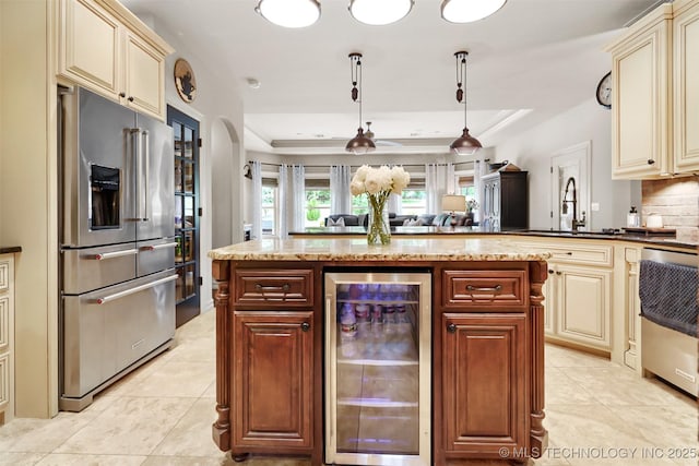 kitchen with sink, beverage cooler, decorative light fixtures, high end refrigerator, and cream cabinetry