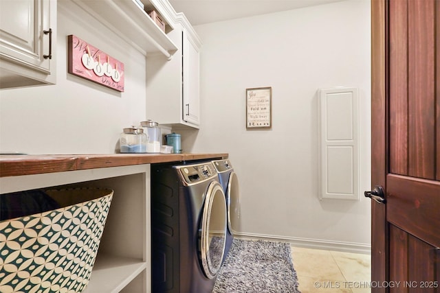 clothes washing area with cabinets, washing machine and clothes dryer, and light tile patterned floors