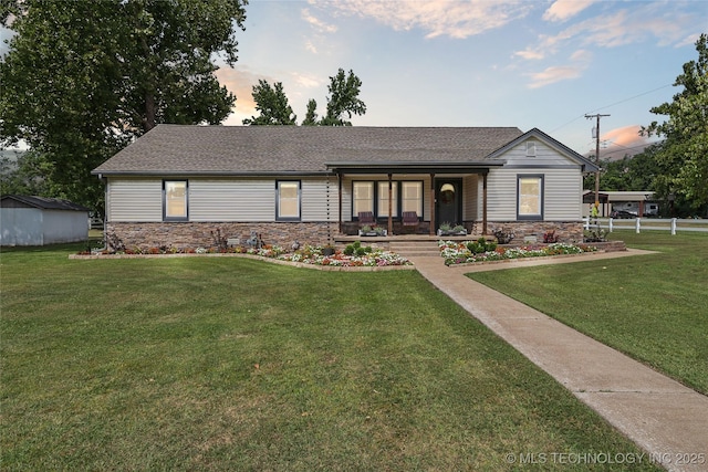 view of front of house with a porch, a storage unit, and a lawn