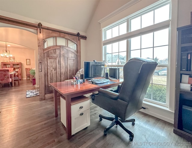 office area featuring hardwood / wood-style flooring, vaulted ceiling, and a barn door