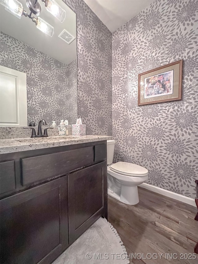 bathroom featuring wood-type flooring, toilet, and vanity