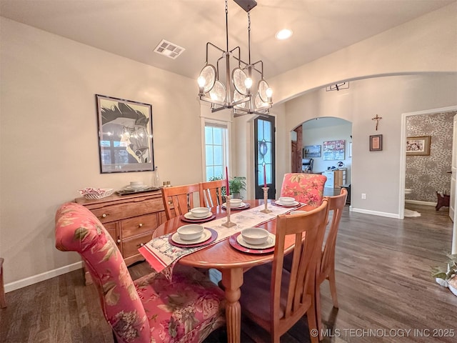 dining area featuring dark wood-type flooring and an inviting chandelier