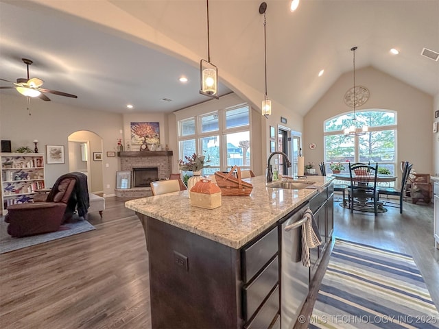 kitchen featuring hanging light fixtures, a brick fireplace, sink, and a center island with sink