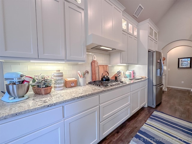 kitchen with dark hardwood / wood-style floors, tasteful backsplash, white cabinetry, light stone counters, and stainless steel appliances