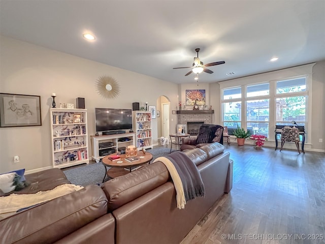 living room featuring wood-type flooring, ceiling fan, and a fireplace