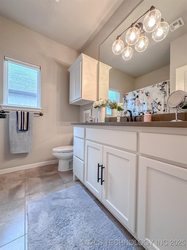 bathroom with tile patterned floors, plenty of natural light, toilet, and vanity