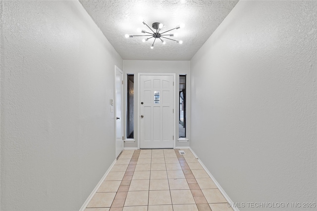 entryway featuring a chandelier, a textured ceiling, and light tile patterned flooring