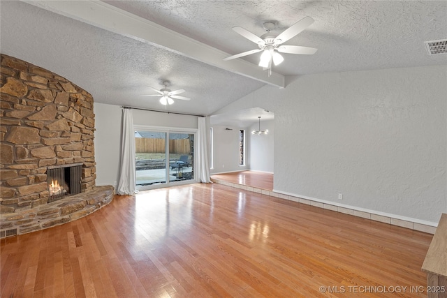 unfurnished living room with a stone fireplace, vaulted ceiling with beams, a textured ceiling, hardwood / wood-style flooring, and ceiling fan with notable chandelier