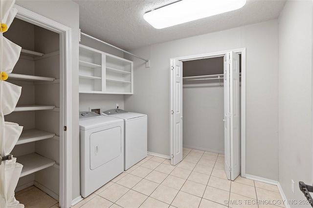 laundry room featuring a textured ceiling, washing machine and clothes dryer, and light tile patterned flooring