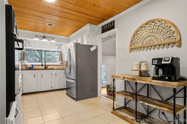 kitchen with stainless steel refrigerator with ice dispenser, ornamental molding, sink, and white cabinets