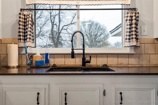 details with white cabinetry, sink, tasteful backsplash, and dark stone countertops