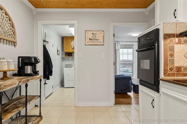 kitchen with tasteful backsplash, washer / dryer, oven, light tile patterned floors, and crown molding