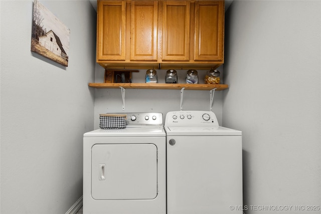 clothes washing area with washing machine and dryer and cabinets