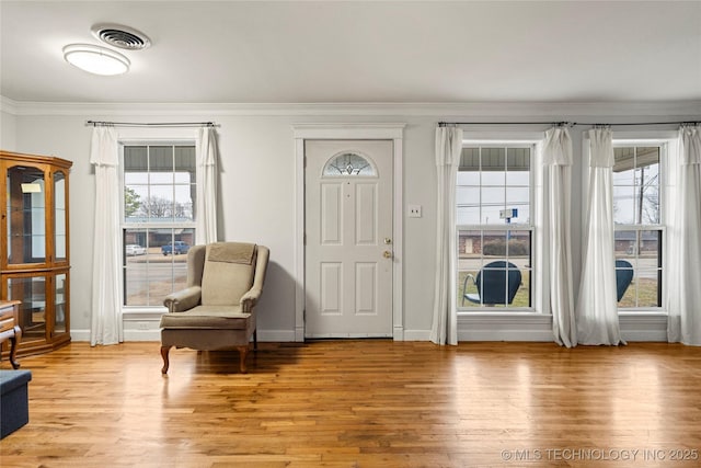 entryway with crown molding, a wealth of natural light, and light wood-type flooring