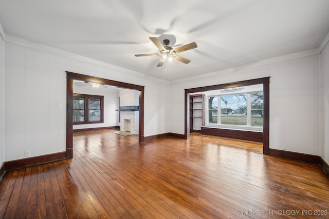 unfurnished room with hardwood / wood-style flooring, ceiling fan, and a fireplace