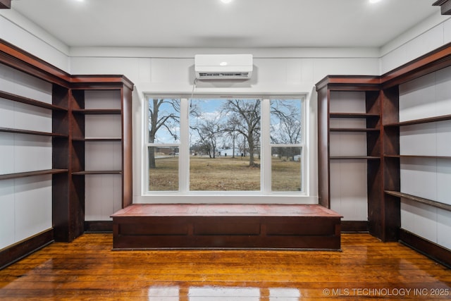 spacious closet featuring an AC wall unit and dark hardwood / wood-style flooring