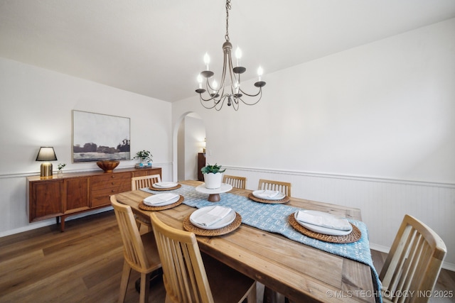 dining space featuring dark wood-type flooring and an inviting chandelier