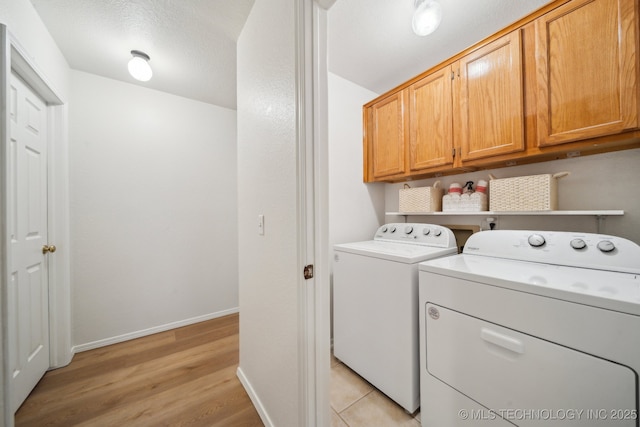 washroom with cabinets, washing machine and clothes dryer, light hardwood / wood-style floors, and a textured ceiling