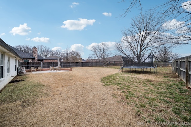 view of yard with a trampoline and a patio area