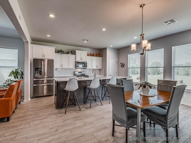 dining area featuring an inviting chandelier, sink, and light wood-type flooring