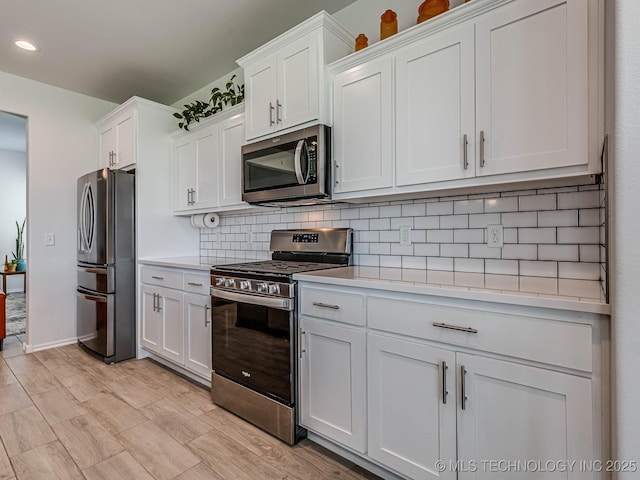 kitchen with backsplash, stainless steel appliances, light hardwood / wood-style floors, and white cabinets