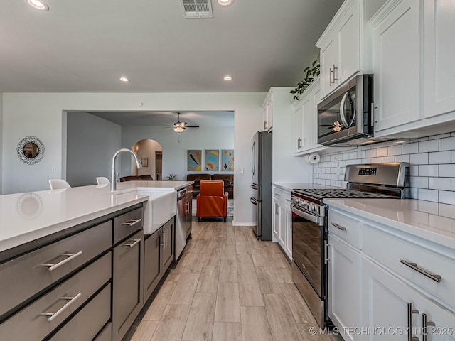 kitchen featuring sink, ceiling fan, appliances with stainless steel finishes, white cabinets, and decorative backsplash