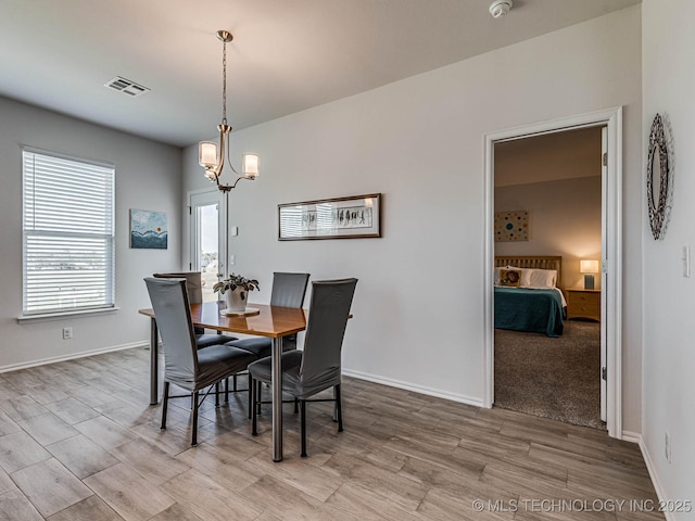 dining space with a notable chandelier and light hardwood / wood-style flooring