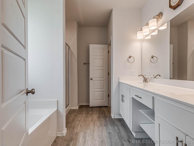 bathroom featuring hardwood / wood-style flooring, vanity, and plus walk in shower