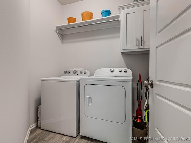 clothes washing area with cabinets, washer and clothes dryer, and light hardwood / wood-style flooring