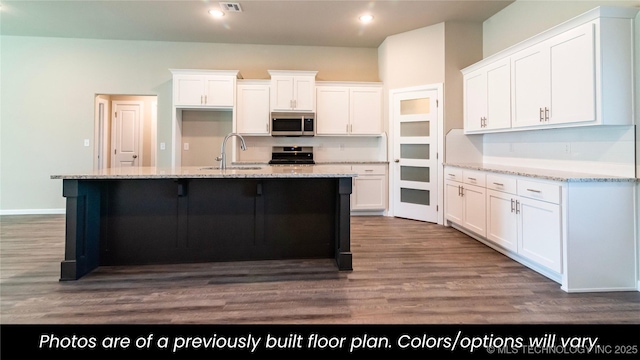 kitchen featuring stainless steel appliances, a center island with sink, white cabinets, and light stone counters