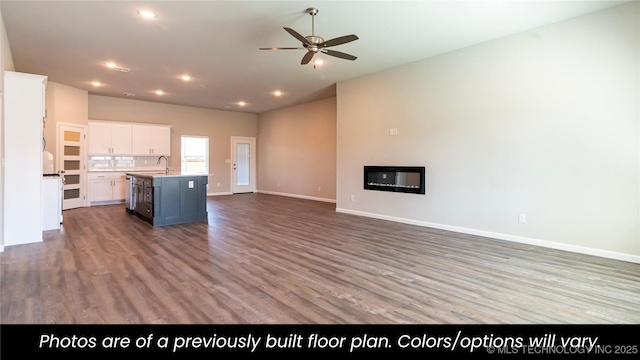 kitchen featuring sink, ceiling fan, white cabinetry, wood-type flooring, and a center island with sink