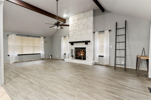 unfurnished living room featuring beam ceiling, ceiling fan, a fireplace, and light hardwood / wood-style floors