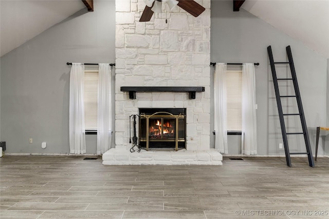 unfurnished living room featuring ceiling fan, a stone fireplace, high vaulted ceiling, and beamed ceiling