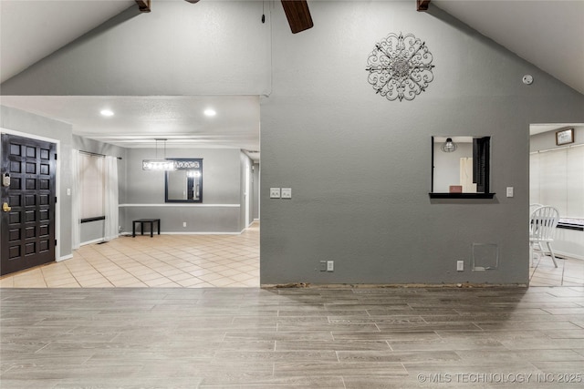 unfurnished living room featuring ceiling fan and high vaulted ceiling