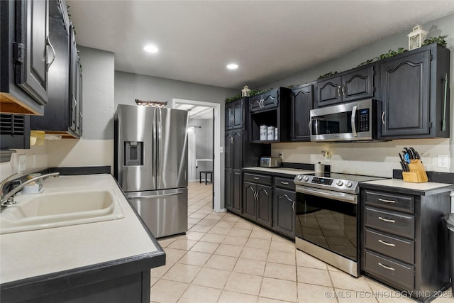 kitchen with sink, light tile patterned flooring, and appliances with stainless steel finishes