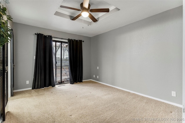 empty room featuring ceiling fan, a raised ceiling, and carpet floors