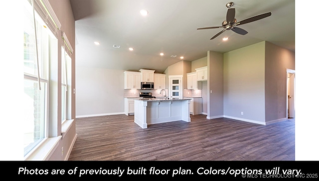 kitchen featuring sink, decorative backsplash, white cabinets, and a center island with sink