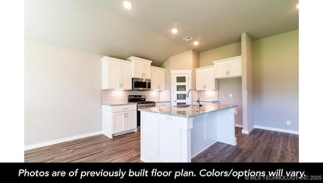 kitchen featuring appliances with stainless steel finishes, sink, white cabinets, a kitchen island with sink, and light stone counters