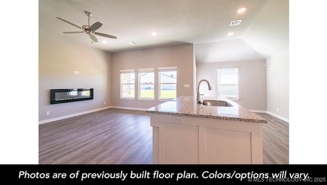 kitchen with sink, white cabinets, dark hardwood / wood-style flooring, a kitchen island with sink, and light stone counters