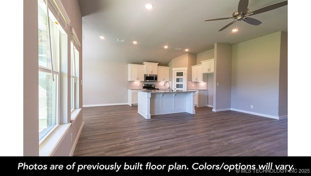 kitchen featuring appliances with stainless steel finishes, sink, white cabinets, decorative backsplash, and a center island with sink