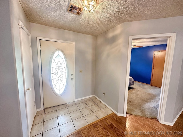 foyer entrance featuring a textured ceiling and light wood-type flooring