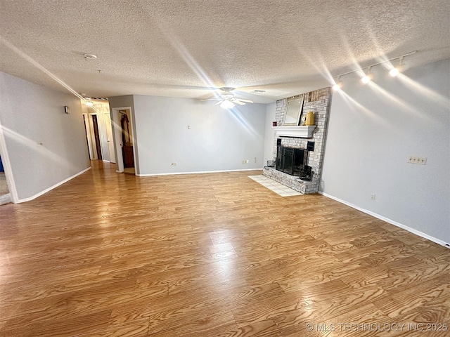 unfurnished living room featuring wood-type flooring, a textured ceiling, ceiling fan, and a fireplace