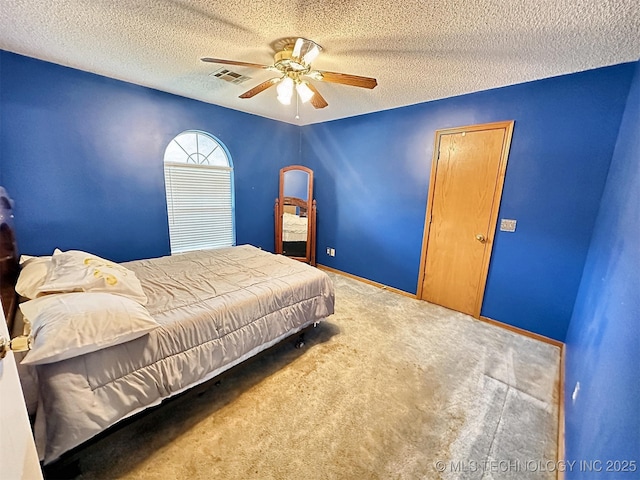 carpeted bedroom with ceiling fan and a textured ceiling